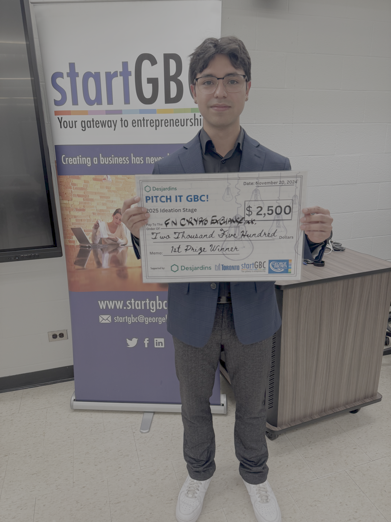 Anthony Huete-Jacobs holding a first-place $2,500 pitch competition award