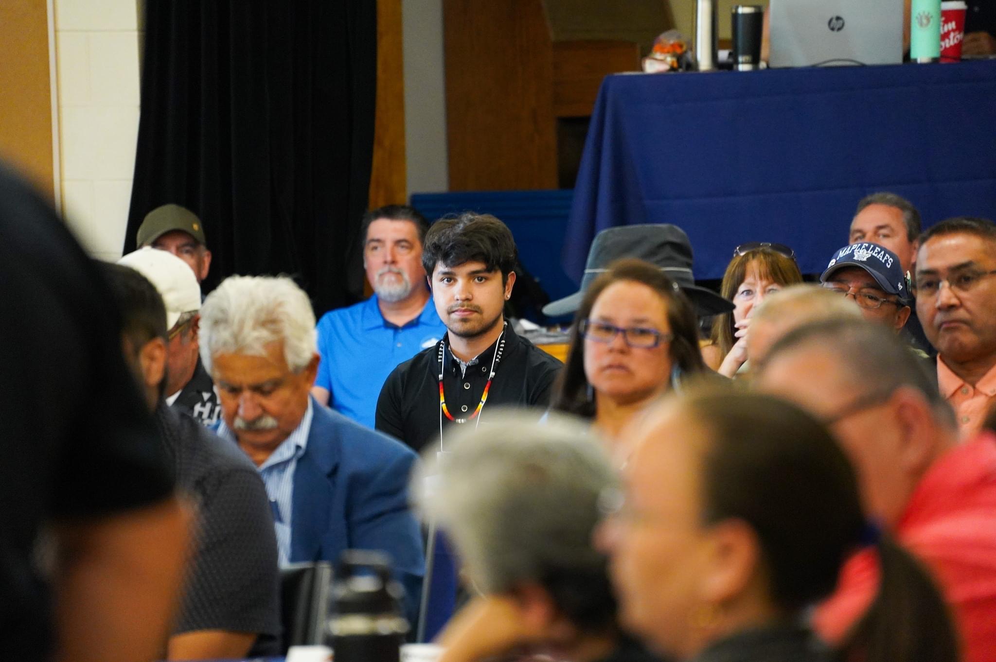Anthony Huete-Jacobs seated among community members at a gathering