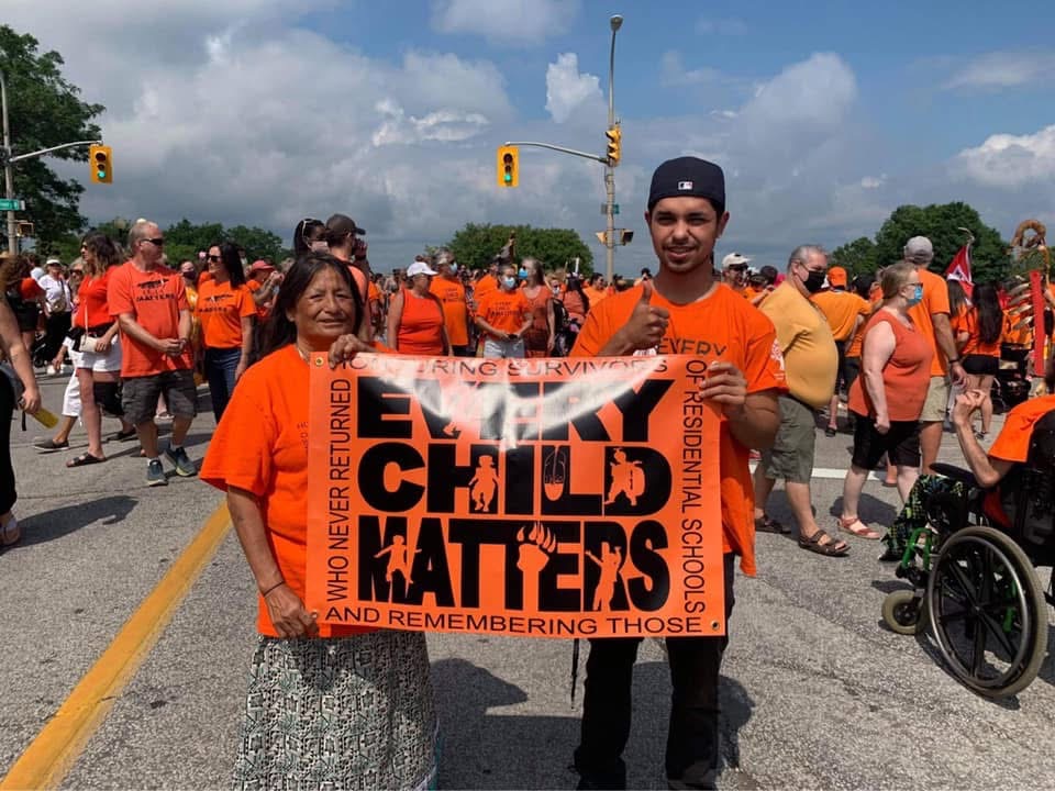 Anthony and his grandmother Audrey Jacobs wearing orange shirts and holding an Every Child Matters banner on the National Day for Truth and Reconciliation